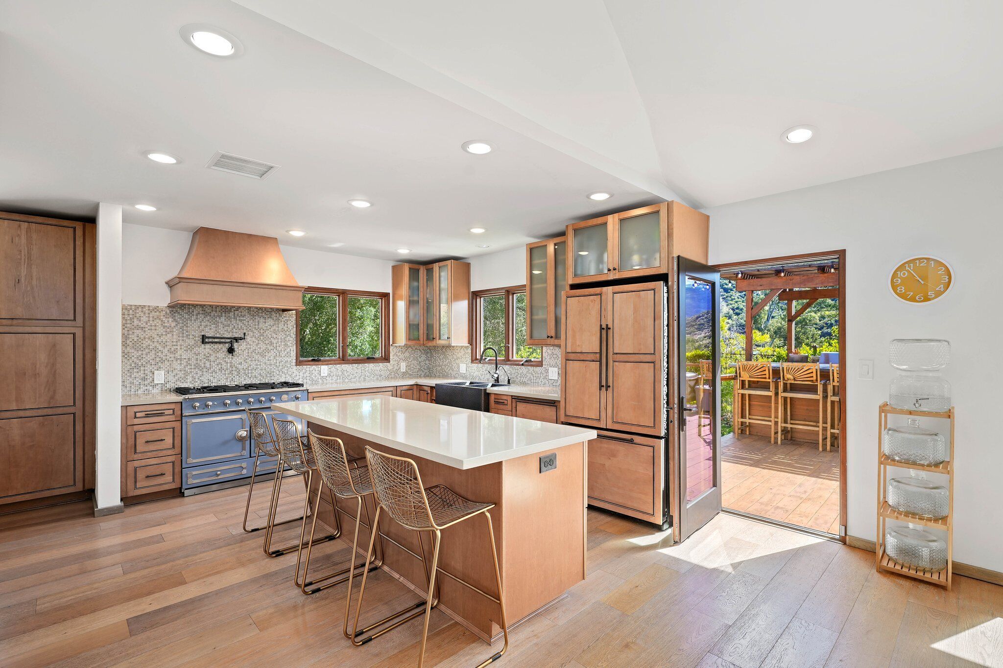 Chef’s kitchen with La Cornue range, oversized island, and doors opening to the deck bar