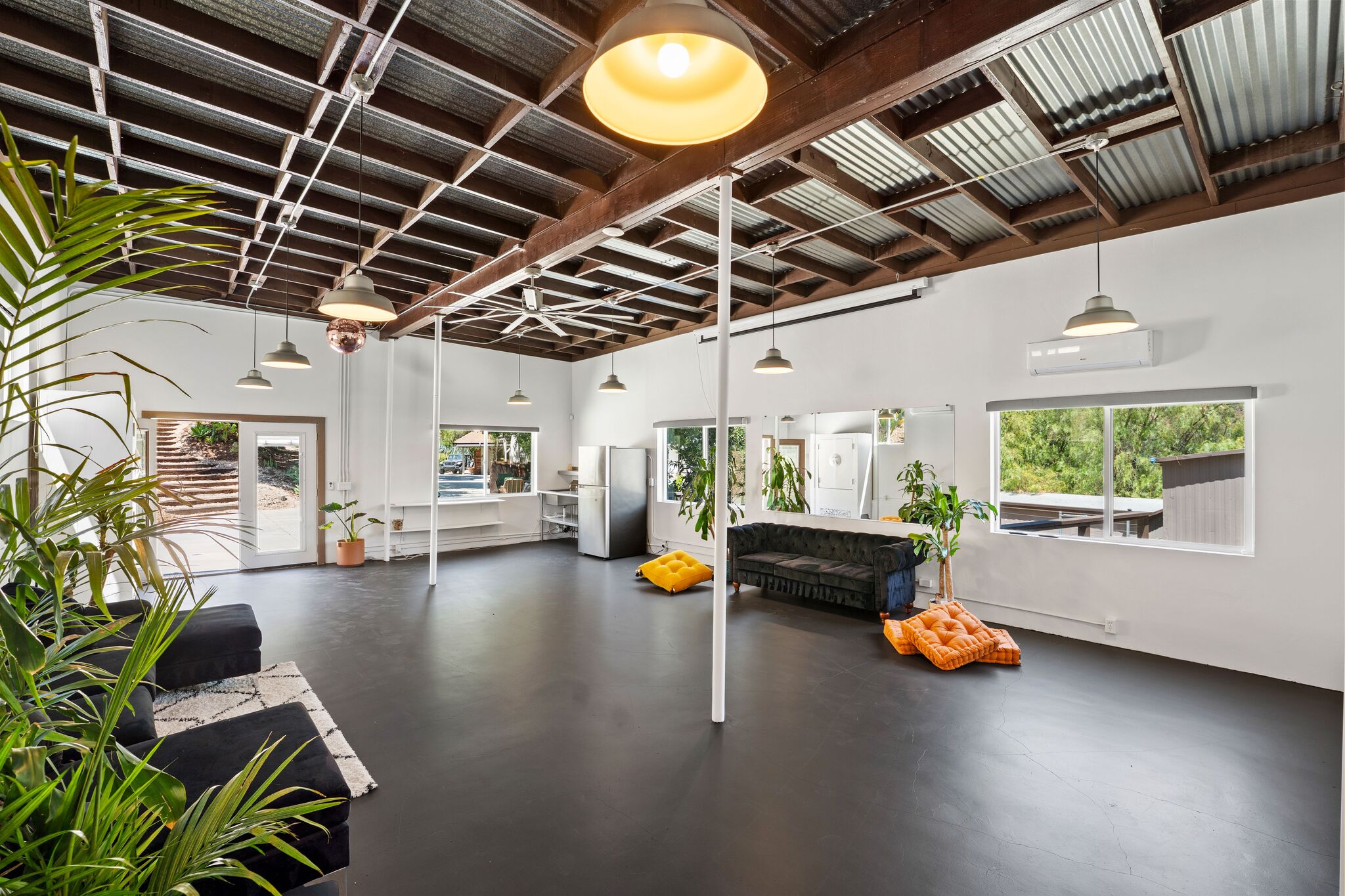 Wide-open studio interior with corrugated ceiling, kitchenette, and lounge seating