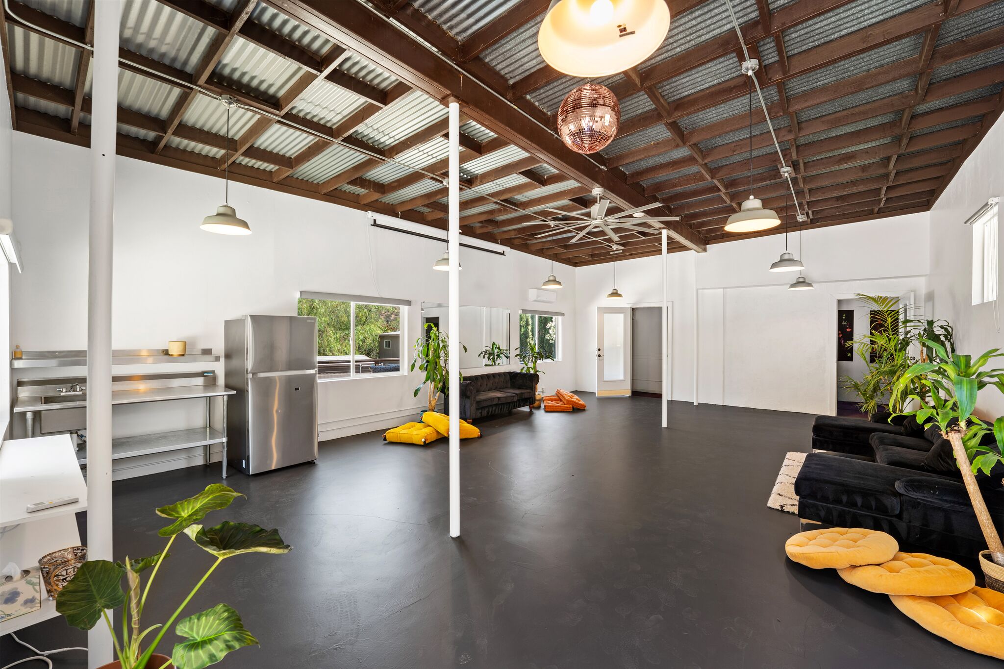 Open studio interior with corrugated ceiling, lounge seating, and a disco ball