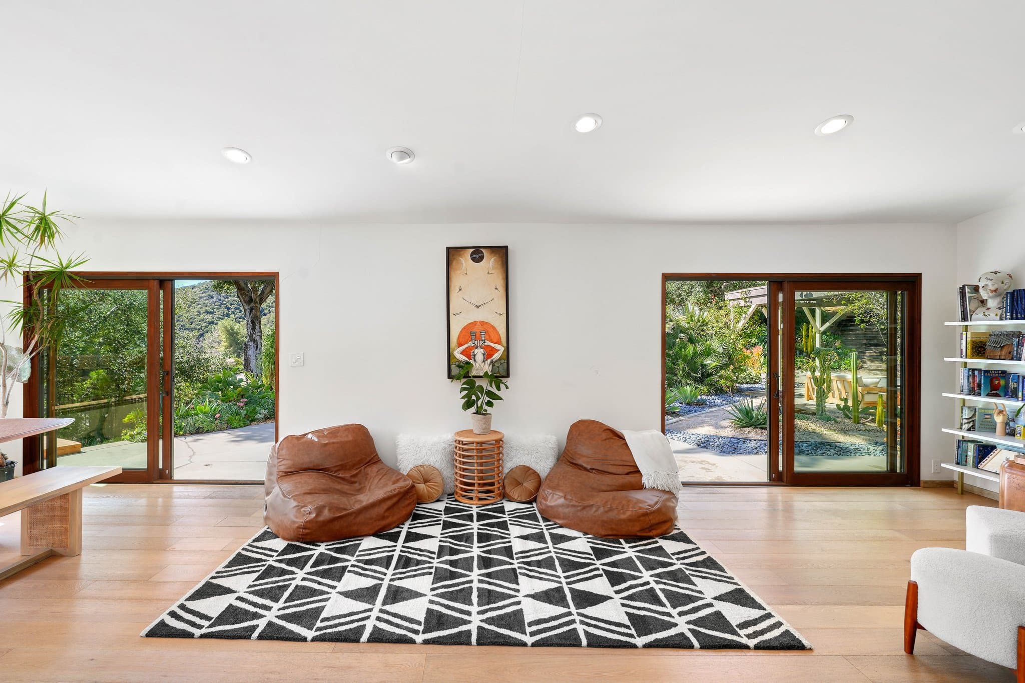 Boho lounge with leather poufs and sliding doors opening to the gardens