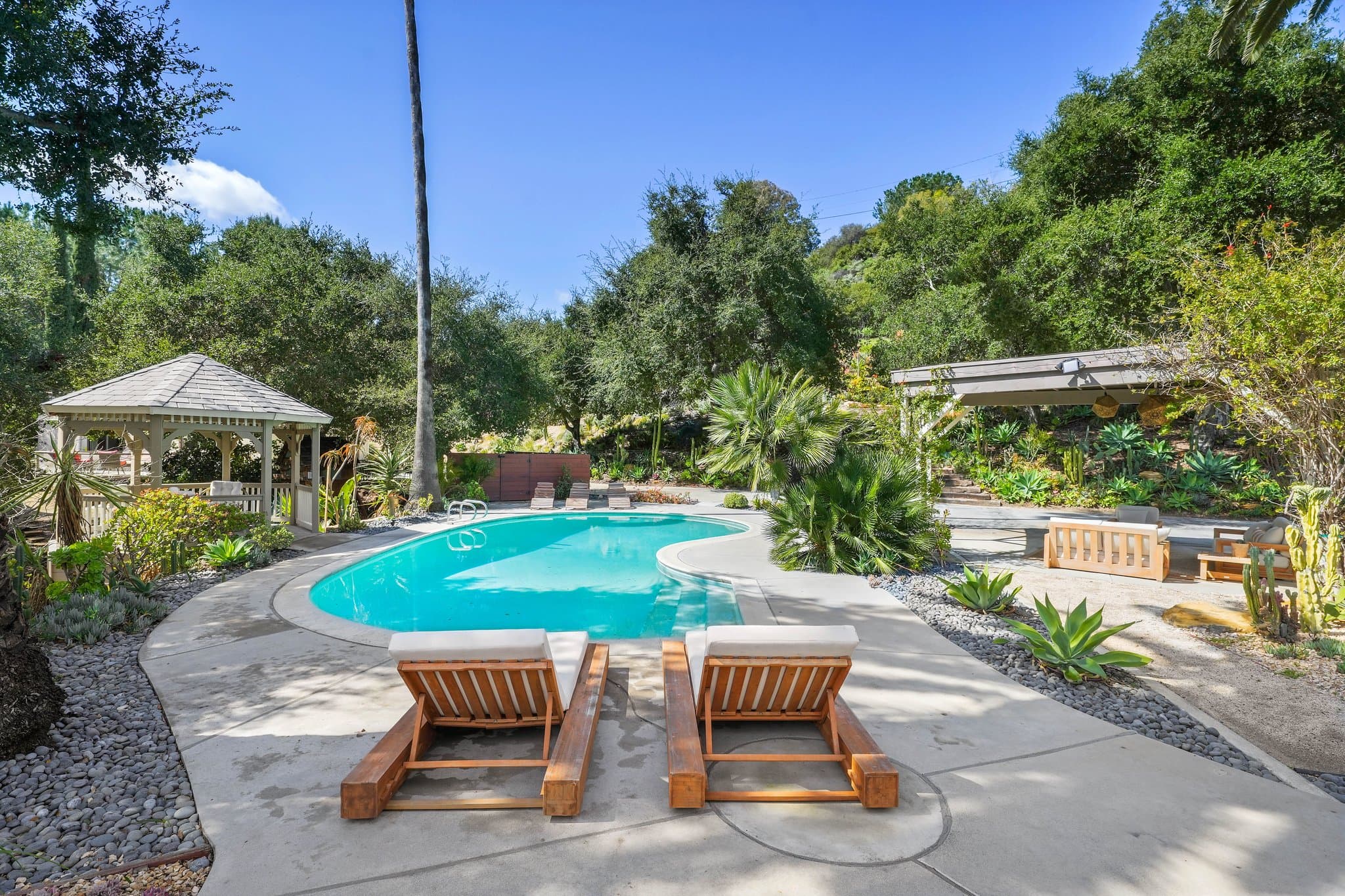 Saltwater pool with wooden loungers and the gazebo at golden hour